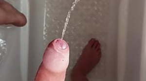 Jerking piss out of an uncut cock in the shower